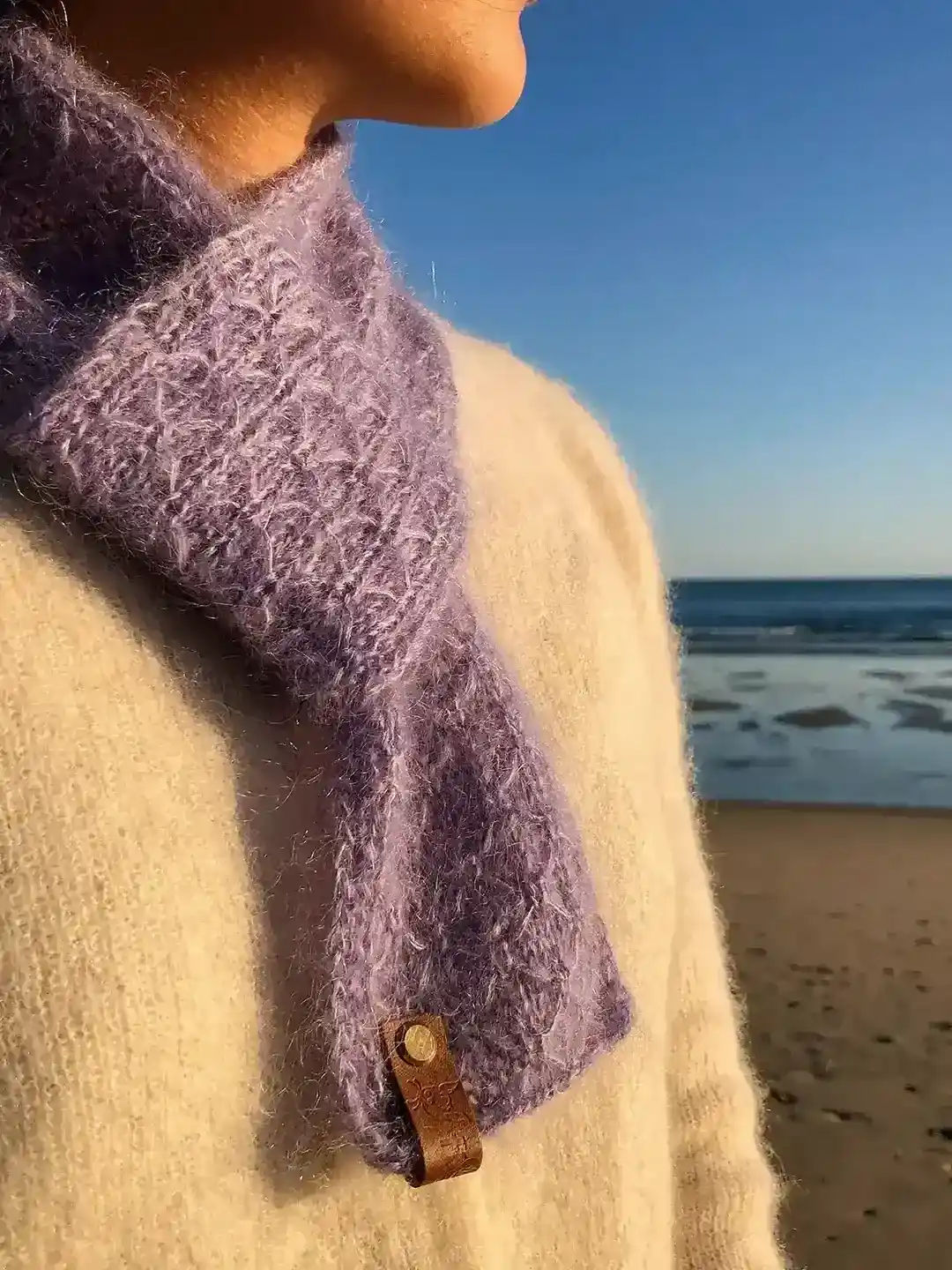 lilac hand knitted wool scarf made of natural fibres with trellis pattern on a beach in vila real de santo antonio algarve