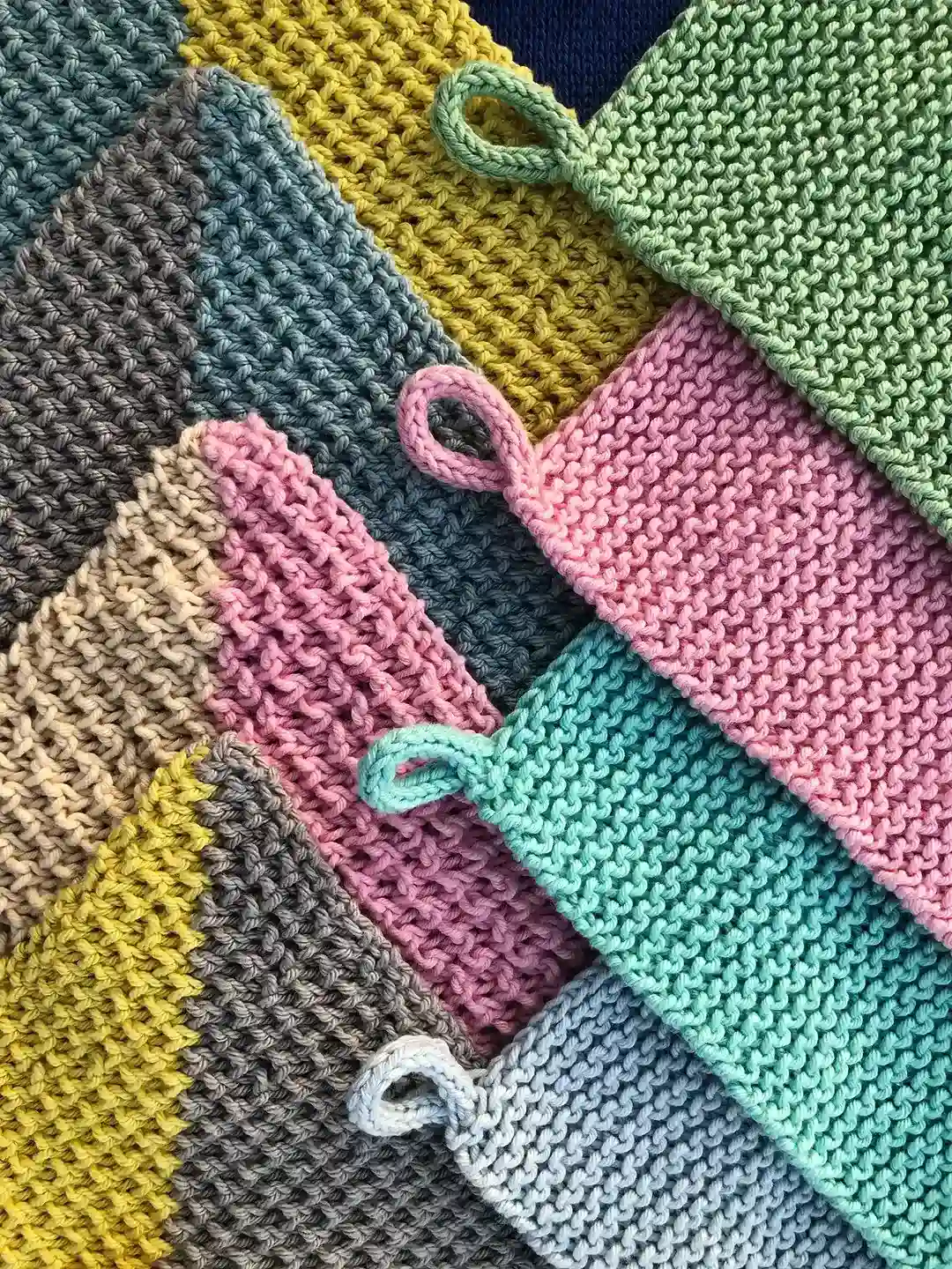 close up view of handmade dishcloths knitted from cotton of blue yellow salad pink turquoise and gray colors