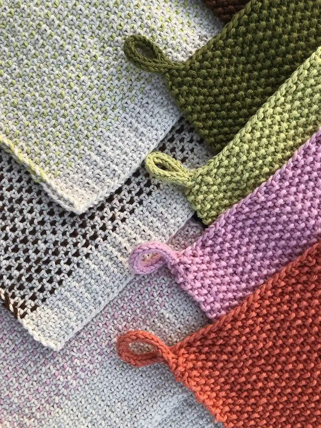 close up view of hanmade dishcloths knitted from cotton off white khaki salad pink and terracotta colors