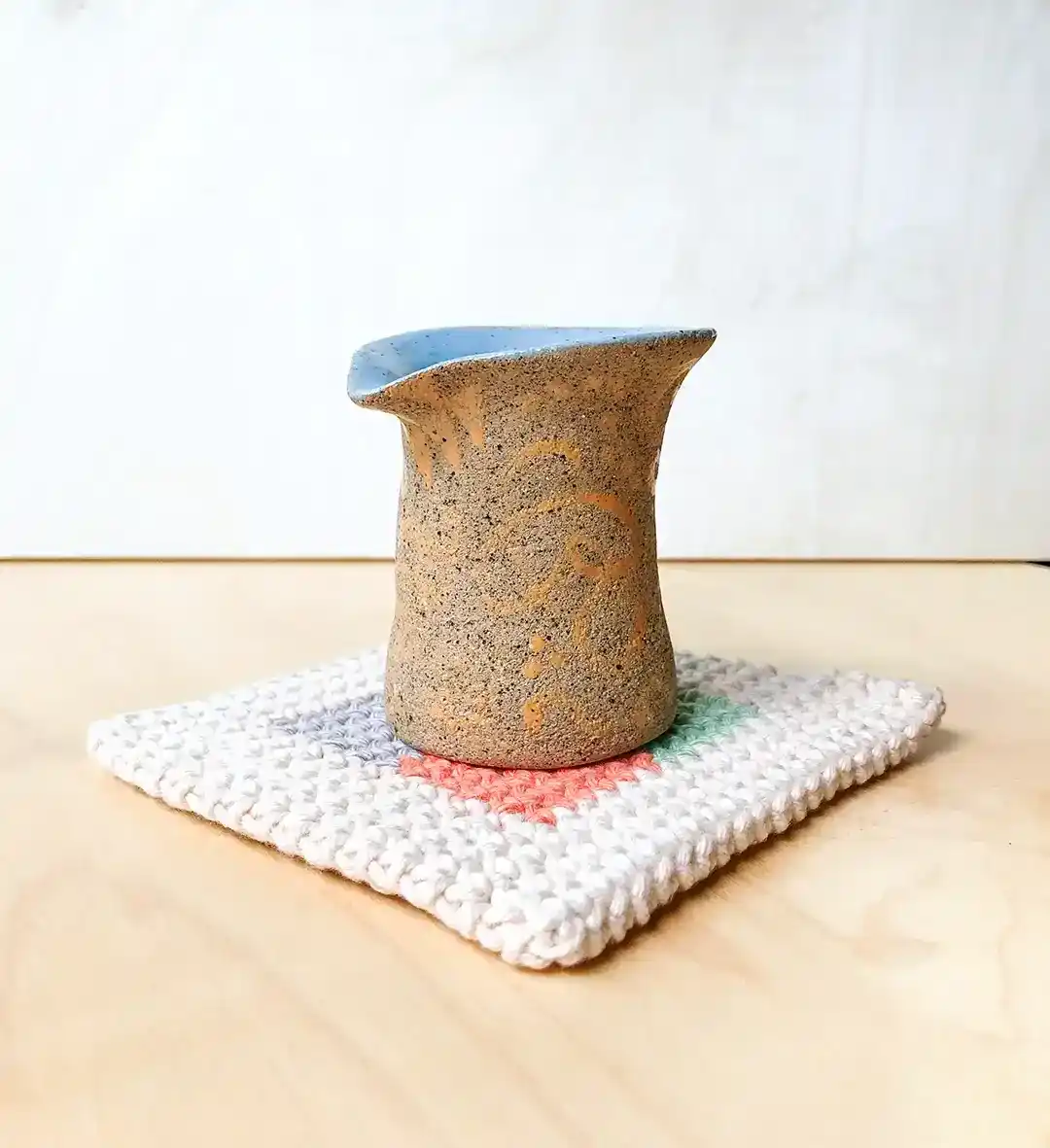 handmade pouring jug with sky blue glaze inside and typographic brushing outside