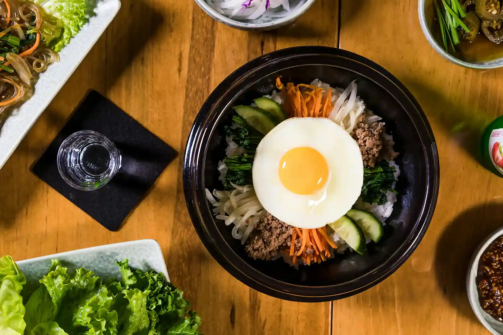 bibimbap made with authentic korean ingredients in black bowl on wooden table
